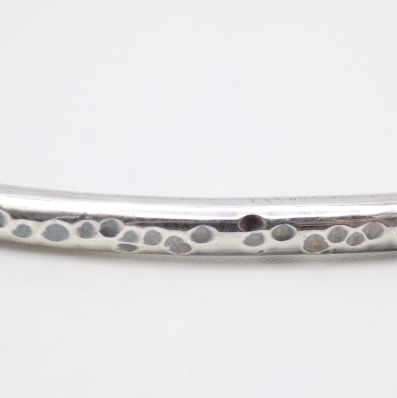 Photo d'un gros plan d'un bracelet en argent légèrement martelé en forme de petit rond.