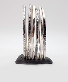 Photo de bracelets joncs en argent massif posés sur un support gris afin qu'ils puissent tenir debout