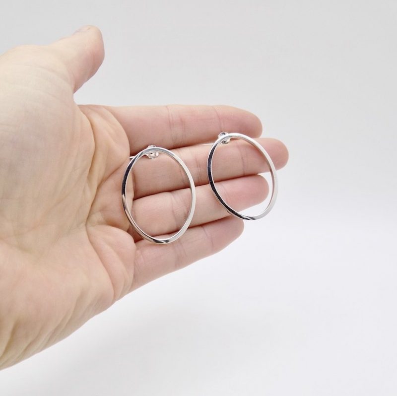 Photo boucles d'oreilles dans une main de face afin de définir leur taille. Boucles ovales en argent 925.