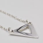 Photo gros plan d'une partie d'un collier en argent. Le gros plan est fait sur le triangle découpé.