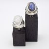 Cette photo montre deux bahues l'une à coté de l'autre disposées sur un support. Ces sont le même modèle mais avec une pierre différente. L'une est sertie d'une Labradorite et l'autre d'une pierre de lune.