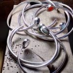 Photo couleur de bracelets ouverts en argent. Les bracelets sont sertis de pierres naturelles rondes de toutes les couleurs.