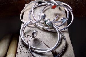 Photo couleur de bracelets ouverts en argent. Les bracelets sont sertis de pierres naturelles rondes de toutes les couleurs.