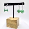 Photo couleur de deux paires de boucles d'oreilles. Elles sont accrochées à un support pour boucles en bois et metal noir. Une paire est composée de perle d'agate verte de 8mm et l'autre est composée de perle d'agate verte aussi de 12mm
