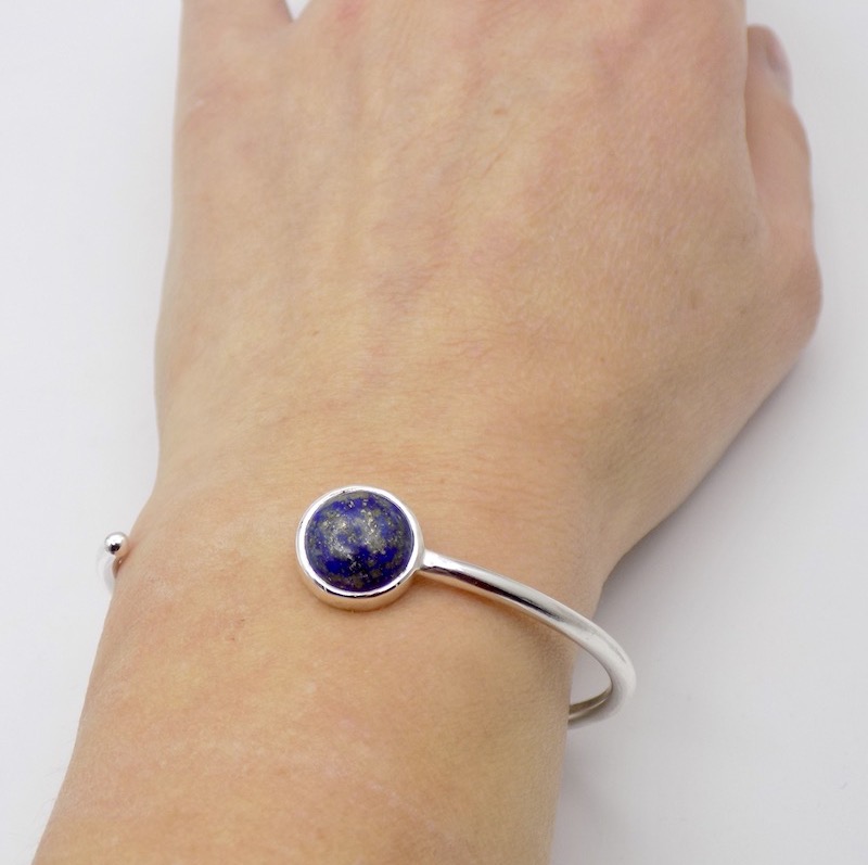 Photo d'un poignet portant un bracelet jonc ouvert est serti d'une pierre bleue. La pierre bleue est une Lapis Lazuli