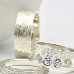 Photo de trois bagues en argent. Deux alliances et une bague de fiançailles serties e trois brillants.