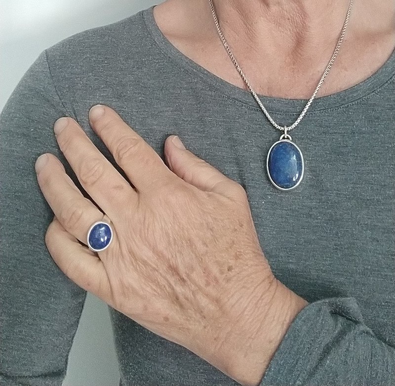 Photo d'un buste de femme portant un pendentif d'un beau cabochon de lapis lazuli et a une bague aussi en lapis lazuli à son doigt.