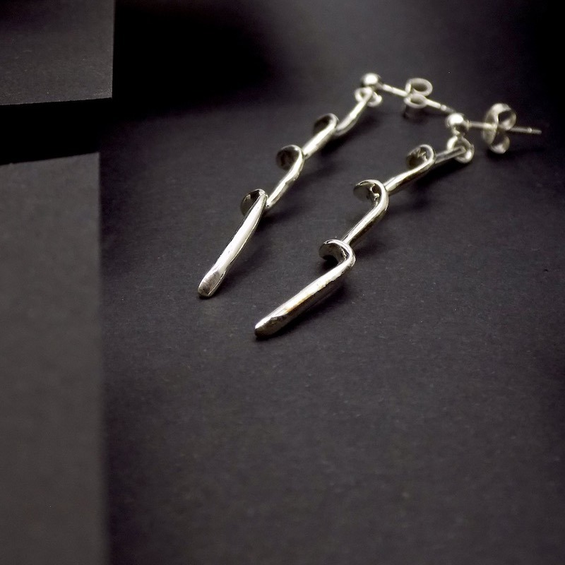 Photo de vue de coté d'une paire de boucles d'oreilles longilignes. Ces boucles sont en argent 925