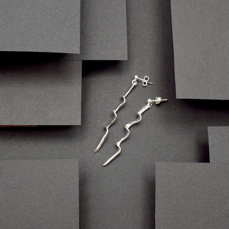 photo couleur d'une paire de boucles d'oreilles posées sur un fond noir hyper design.