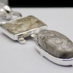 Photo d'un pendentif fait de 2 pierres. Une ovale et l'autre carrée. Elles font comme un totem