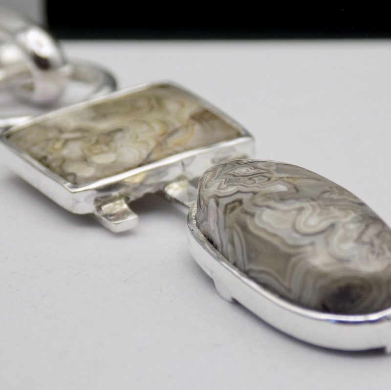 Photo d'un pendentif fait de 2 pierres. Une ovale et l'autre carrée. Elles font comme un totem