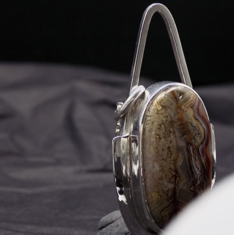 Photo d'un pendentif en argent et pierre d'agate bubble. L'agate est ovale. Ses couleurs sont plutôt dans les bruns et orange.