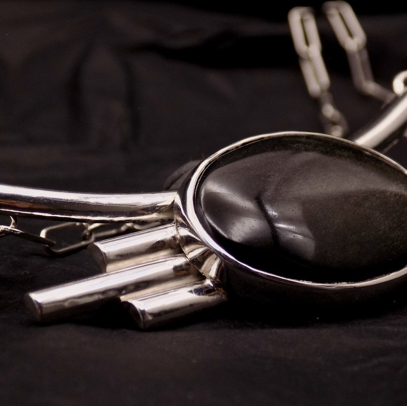 Photo en gros plan d'un collier avec une pierre noire aux reflets dorés.