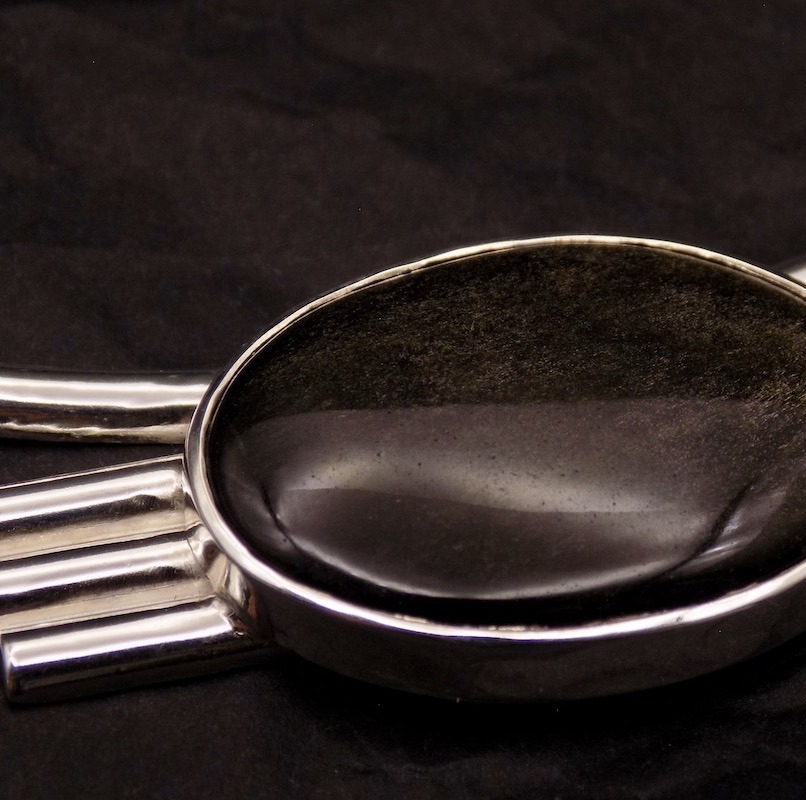 Photo d'une pierre noire obsidienne montée sur un collier un peu plastron en argent