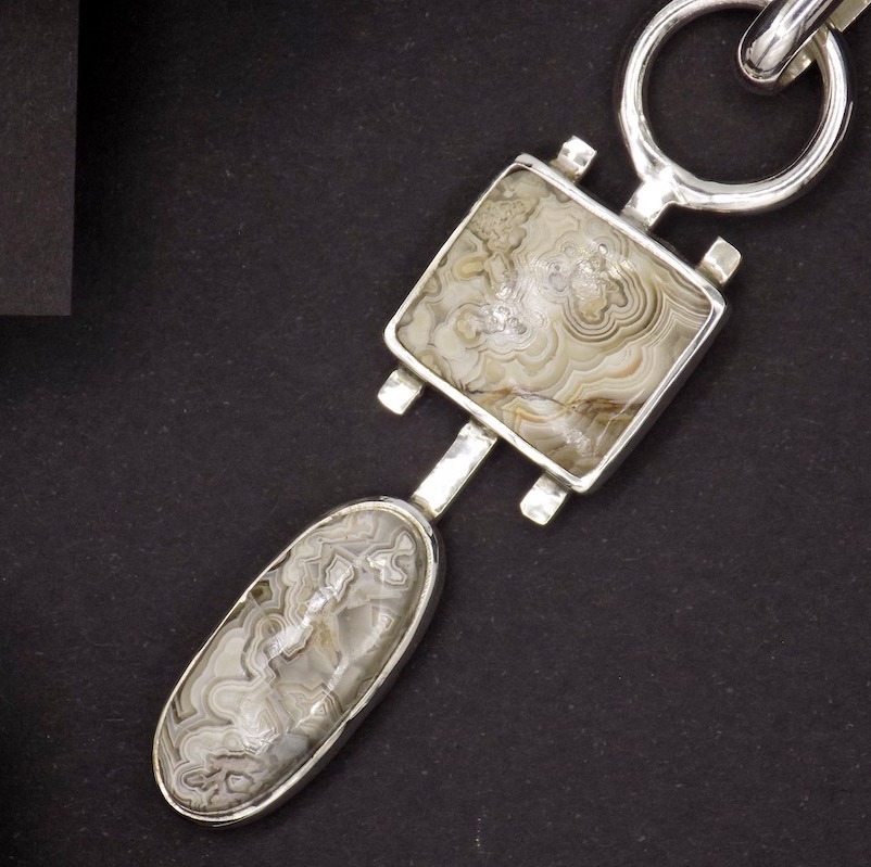 Gros plan sur les pierres qui sont serties sur un pendentif en argent 925. Les pierres sont ovales et carrées. Ce sont des agate crazy lace.