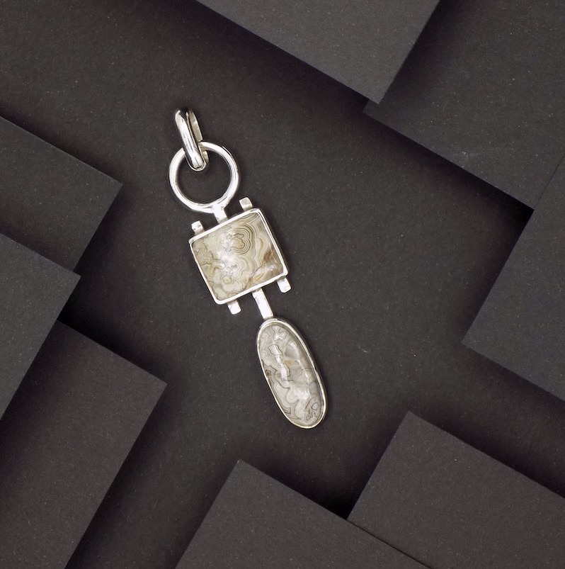 Photo couleur d'un pendentif en argent serti de pierres vue de haut. Les pierres sont des agate crazy lace de couleur marron-beige.
