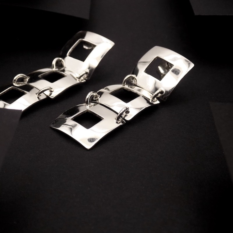 Photo sur fond noir d'une paire de boucles d'oreilles très chic et distinguées en argent massif.