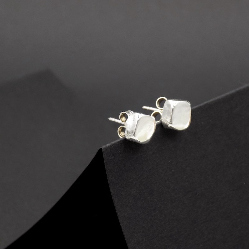 Photo gros plan d'une paire de petite boucles d'oreilles en argent. Forme en pavé.