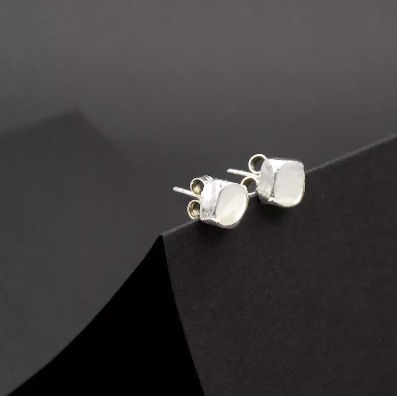 Photo gros plan d'une paire de petite boucles d'oreilles en argent. Forme en pavé.