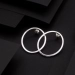 Photo prise en vue de dessus d'une paire de boucles d'oreilles de forme ovale évidée faite en argent 925.