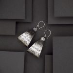 Photo vue de dessus d'une paire de de grandes et grosse paire de boucles d'oreilles. ces boucles sont en argent martelé puis oxydé ce qui leur donne un air vieilli.