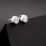 Photo de bijou. Une paire de boucles d'oreilles puce de forme carrée. formée comme un petit pavé en argent massif.
