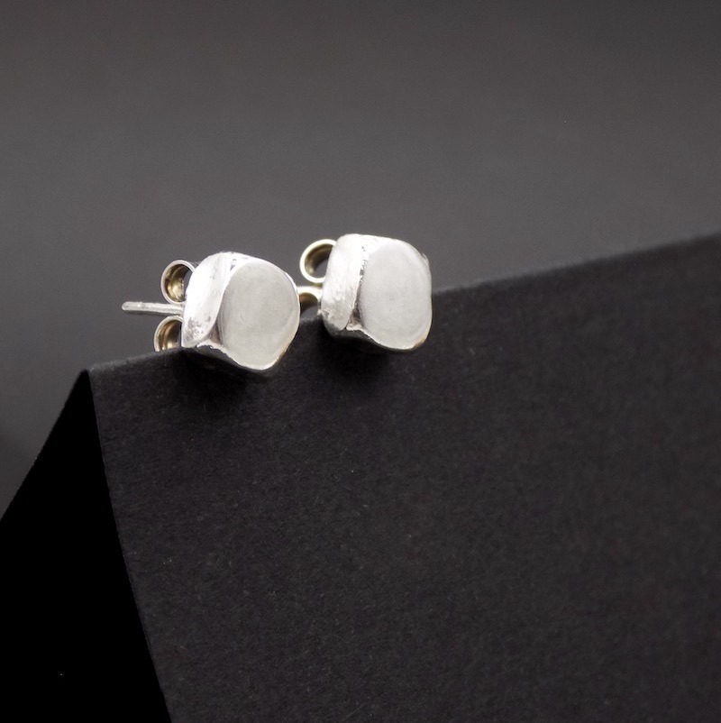 Photo de bijou. Une paire de boucles d'oreilles puce de forme carrée. formée comme un petit pavé en argent massif.