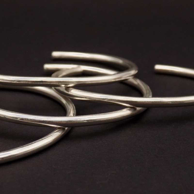 Photo gros plan sur fond noir de bracelet rigide façonnés en argent massif.