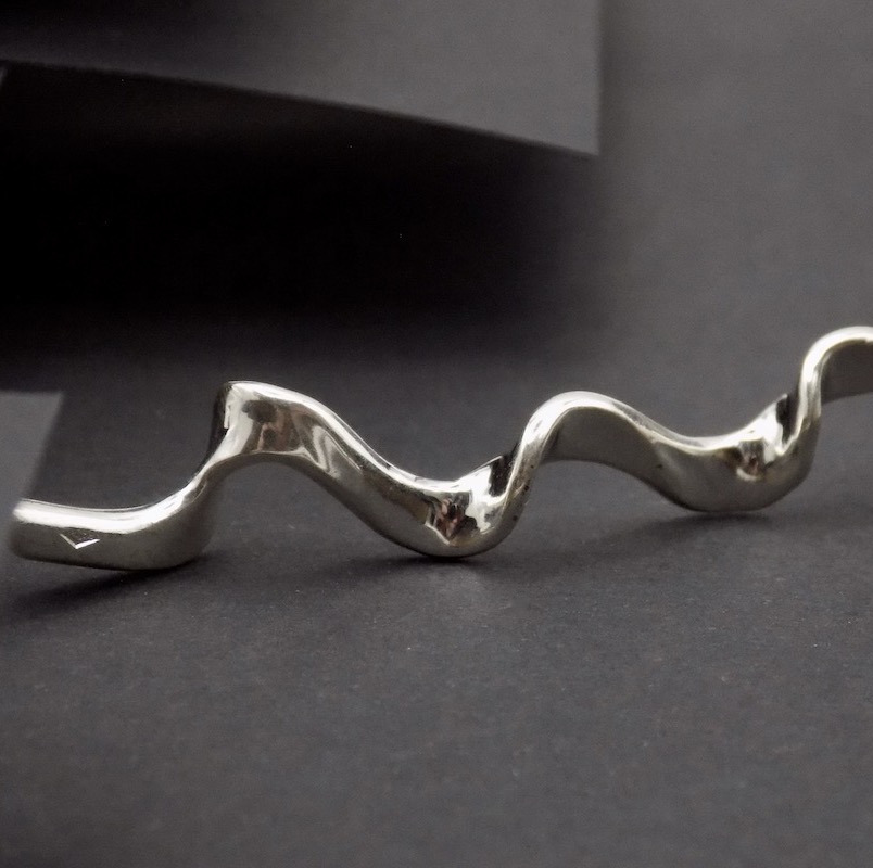 Photo d'un gros plan fait sur bijou de créateur. Ce bijou est un pendentif longiligne réalisé en argent massif.