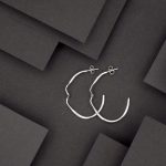 Photo d'une paire de boucles posées sur un fond noir. Paire de créole en argent.