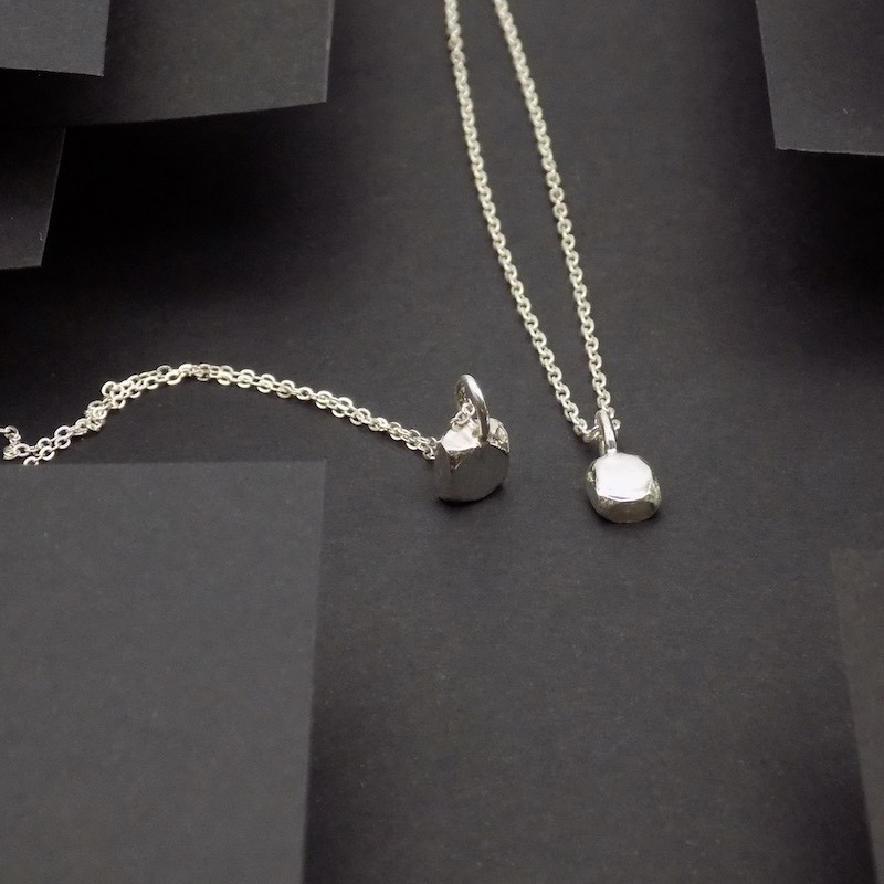 Photo de deux petits pendentifs en argent en forme de pavé.