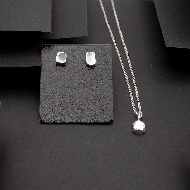 Photo d'un ensemble de boucles d'oreilles et d'un pendentif en forme de pavé. Ces bijoux sont fabriques en argent.