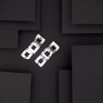 Photo vue de dessus d'une paire de boucles d'oreilles très design. Formées de trois carrés ajourés ce sont des bijoux réalisés artisanalement et en argent massif.