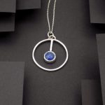 Photo sur fond noir d'un pendentif rond serti d'une pierre de lapis lazuli.