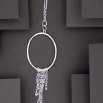 Photo prise de haut montrant un pendentif formé d'un anneau auquel est suspendu plusieurs chaines de différentes longueurs. Cela ressemble comme une méduse.