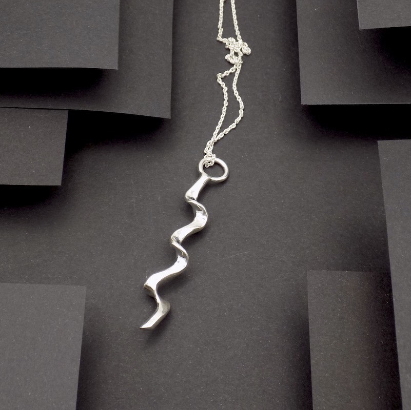 Photo vue de haut d'un pendentif long et en zigzag. Bijou de créateur en argent massif.
