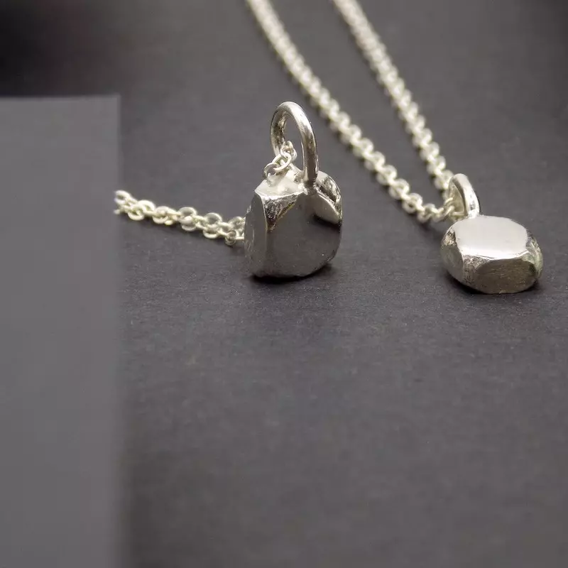 Photo de bijoux sur un fond noir de deux pendentifs faits en argent.