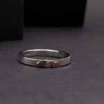 Photo d'une bague en argent posée sur un fond noir. Cette bague est fine mais épaisse. Cuivre et argent