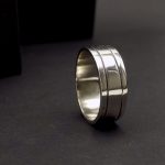 Photo sur fond noir d'une bague en argent925 large. Elle est pour homme. Elle comporte deux sillons de chaque coté