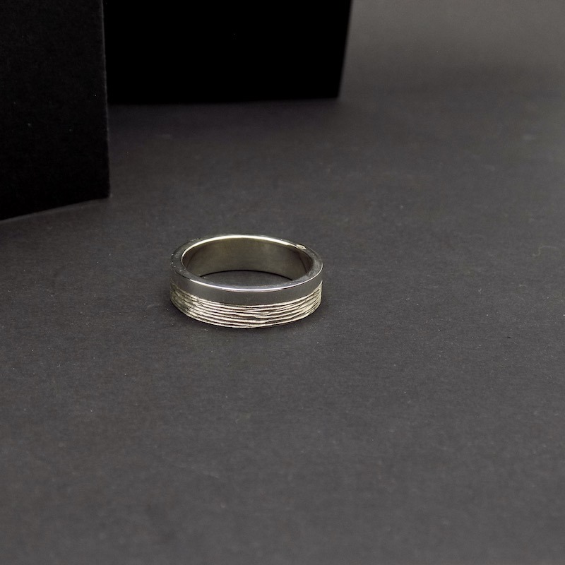 Photo sur fond noir d'une bague posée. C'est une bague en argent massif pour homme