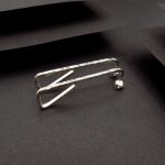 Photo couleur d'une paire de boucles d'oreilles faites en argent 925 à partir d'un fil carré. Elles sont posées sur un fond noir ce qui les fait ressortir.