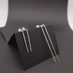 Photo de deux paires de boucles d'oreilles en argent925 longilignes et martelées qui sont posées sur un support noir.
