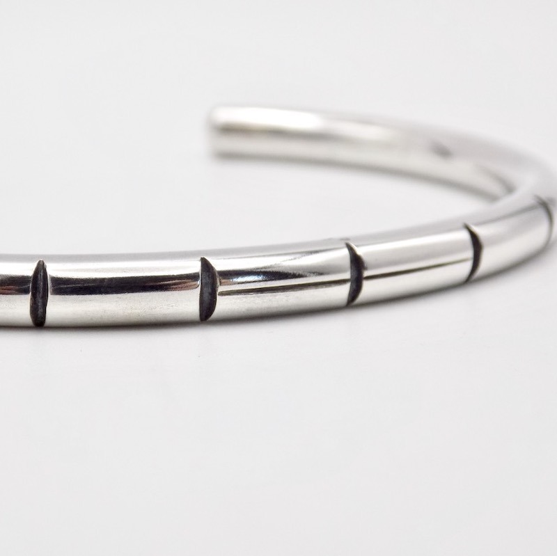Photo gros plan des details d'un bracelet jonc ouvert en argent posé