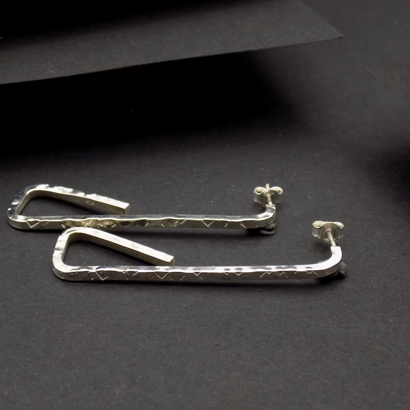 Photo d'une paire de boucle sen argent925 posées sur un fond noir. On peut les voir de profil.