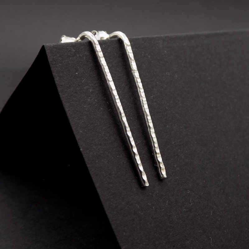 Photo d'une paire de boucles d'oreilles en argent massif posées sur un carton noir