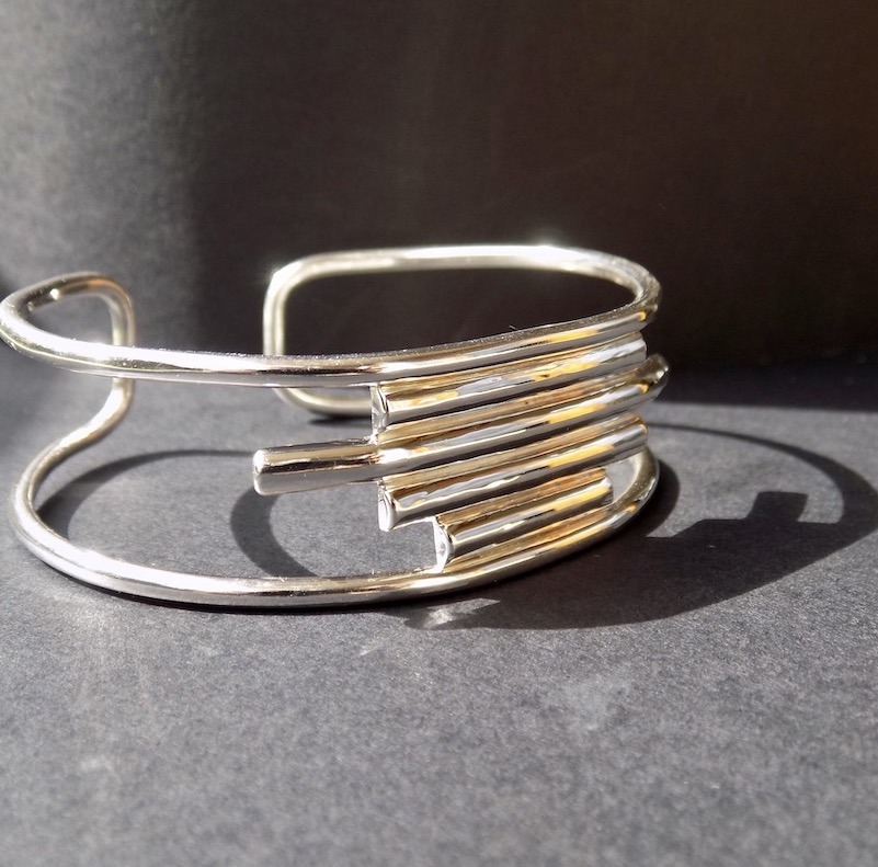 Photo de profil d'un bracelet manchette en argent posé sur un papier noir.