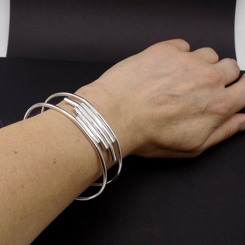 Photo d'un avant bras avec un bracelet manchette en argent massif sur fond noir