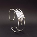 Photo d'un bracelet large dit manchette en argent 925 sur un fond noir.