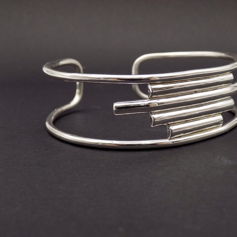 Photo vue légèrement de profil d'un bracelet manchette en argent sur un fond noir