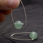 Photo gros plan d'une paire de boucles d'oreilles dont une est prise par deux doigts.